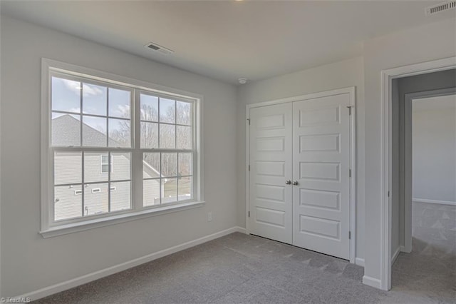 unfurnished bedroom featuring a closet, carpet, visible vents, and baseboards