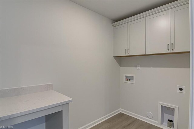 clothes washing area with cabinet space, baseboards, light wood-style flooring, hookup for a washing machine, and electric dryer hookup