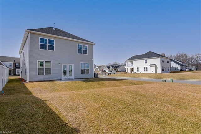 back of property with a residential view, a lawn, and french doors