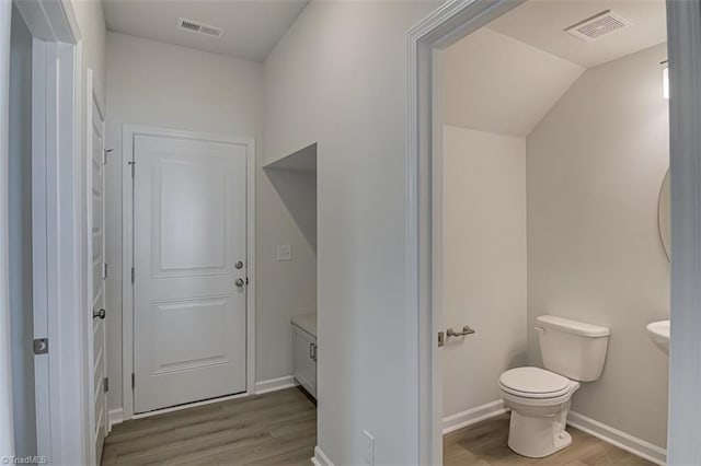 bathroom featuring baseboards, visible vents, toilet, and wood finished floors