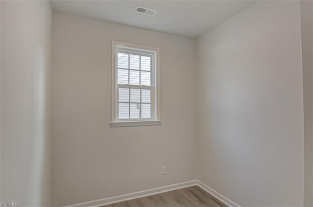 unfurnished room featuring wood finished floors, visible vents, and baseboards