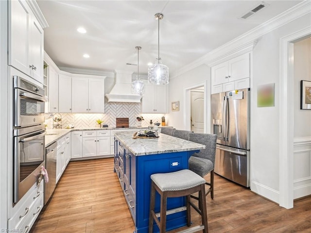 1659 Angus Ridge Dr, Kernersville, NC 27284 - kitchen with stainless steel appliances, white cabinetry, a kitchen breakfast bar, decorative backsplash, and light wood-type flooring