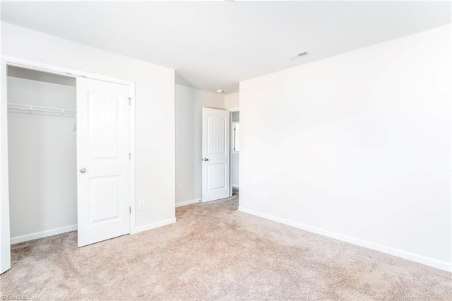 unfurnished bedroom with light colored carpet and a closet