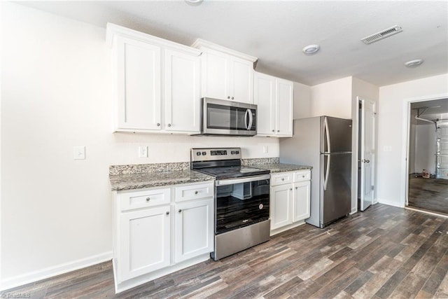 kitchen with light stone counters, dark hardwood / wood-style floors, white cabinets, and appliances with stainless steel finishes