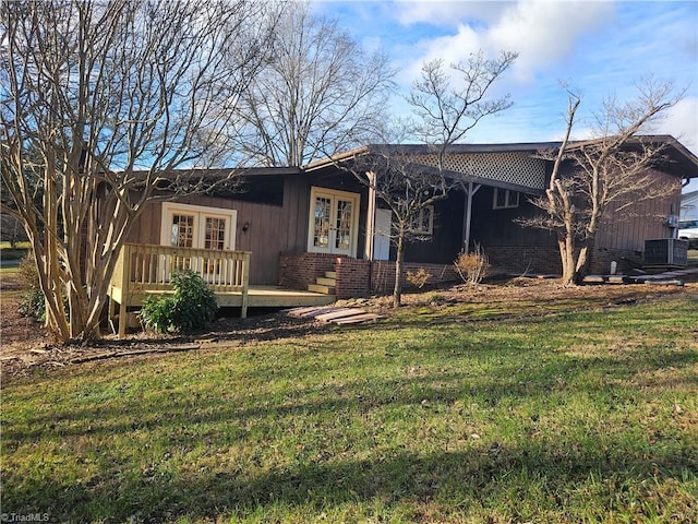 ranch-style house featuring a front yard, french doors, and a deck