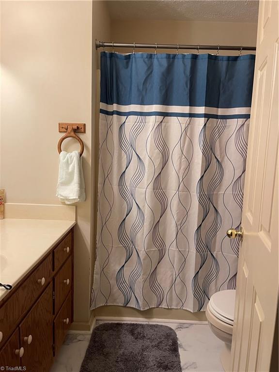 bathroom with vanity, toilet, and a textured ceiling