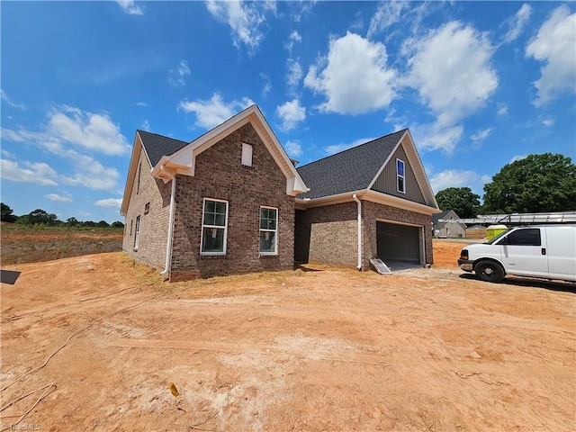 view of property exterior with dirt driveway, an attached garage, and brick siding