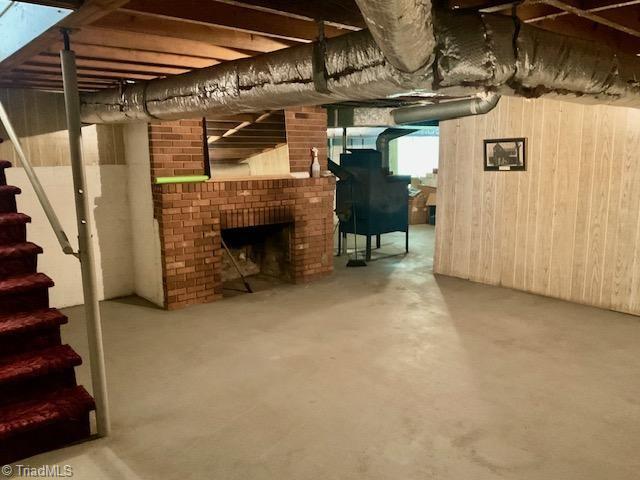 327 Lanier Dr, Lexington, NC 27295 - below grade area with stairs, wooden walls, and a brick fireplace