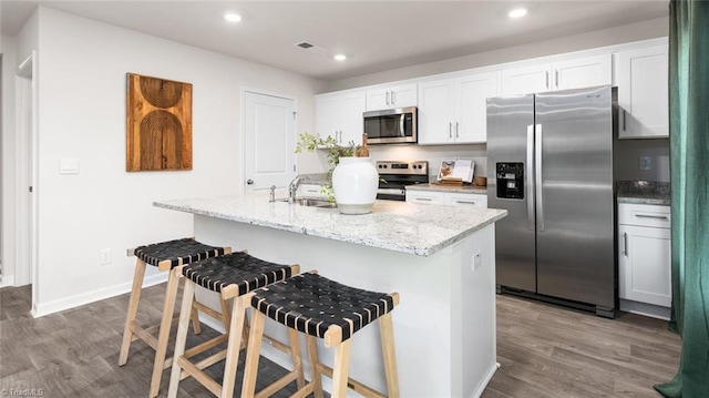 kitchen with white cabinetry, stainless steel appliances, an island with sink, and a breakfast bar