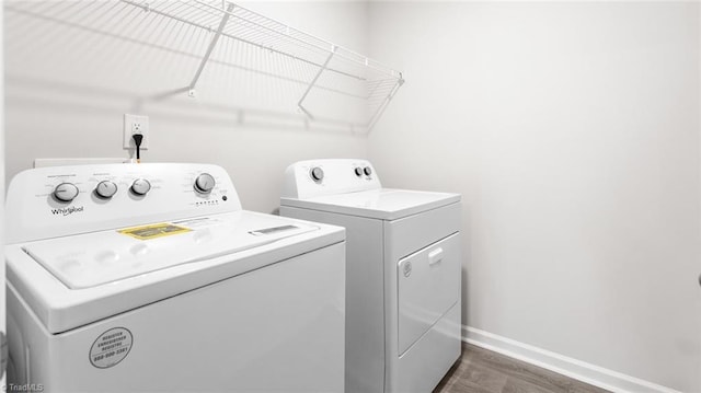 clothes washing area with washing machine and dryer and dark hardwood / wood-style floors