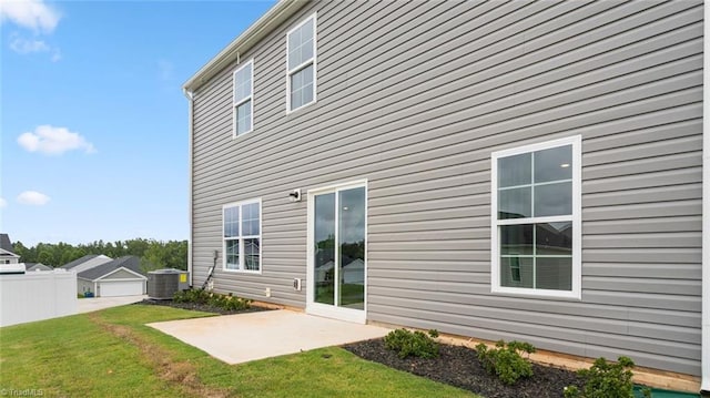 rear view of house with central AC unit, a patio area, and a lawn