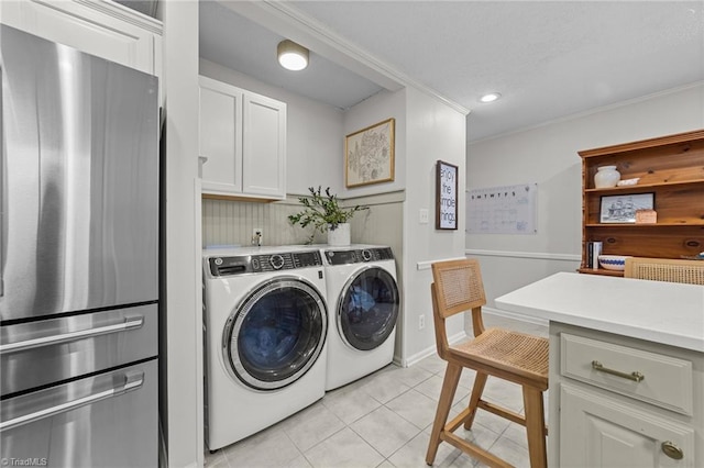 clothes washing area featuring cabinets, washer and dryer, and light tile patterned flooring