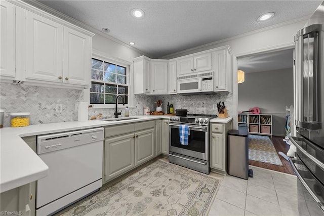 kitchen featuring sink, white cabinets, light tile patterned floors, stainless steel appliances, and a textured ceiling