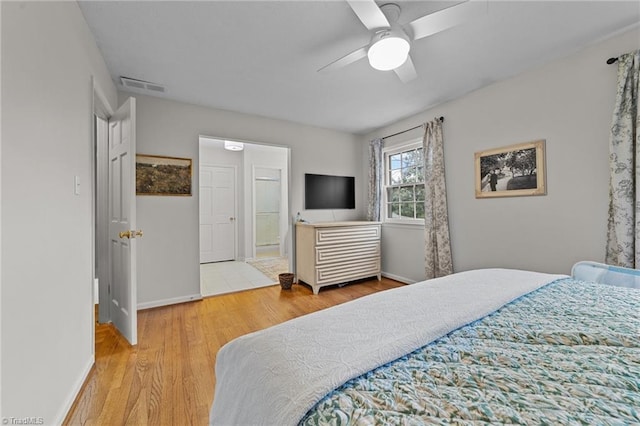 bedroom with wood-type flooring, ceiling fan, and ensuite bath