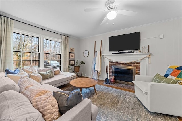 living room featuring a brick fireplace, hardwood / wood-style flooring, ornamental molding, and ceiling fan