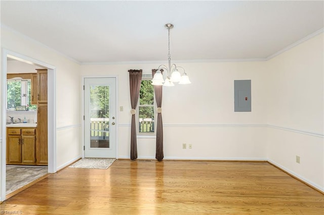 unfurnished dining area featuring a chandelier, crown molding, electric panel, and light wood-type flooring