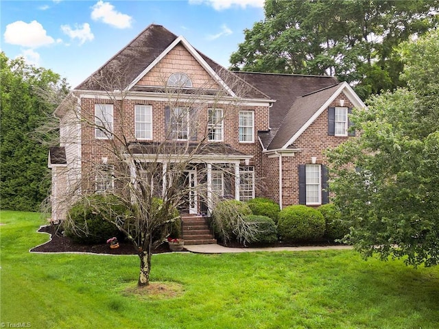 15 Orchard Grass Ct, Greensboro, NC 27410 - colonial house featuring brick siding, a front lawn, and roof with shingles