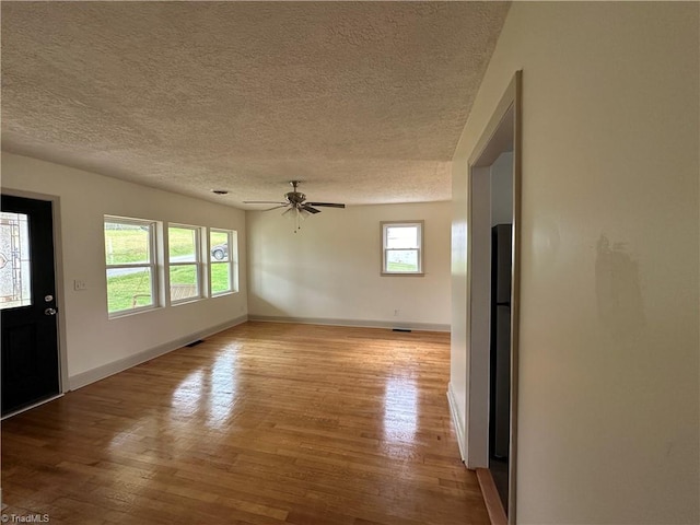 unfurnished living room featuring ceiling fan, a textured ceiling, and light hardwood / wood-style flooring