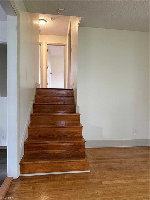 stairs with hardwood / wood-style flooring and a textured ceiling