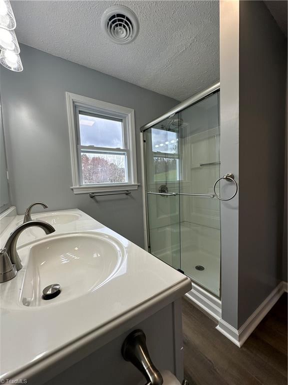 bathroom featuring vanity, a textured ceiling, hardwood / wood-style flooring, and a shower with door