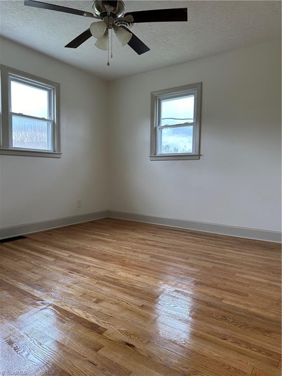 empty room featuring ceiling fan, a textured ceiling, and light wood-type flooring