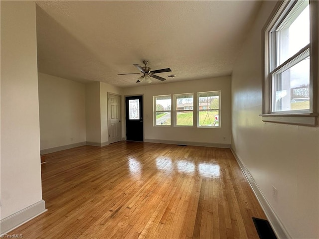 interior space with ceiling fan, light hardwood / wood-style flooring, and a textured ceiling