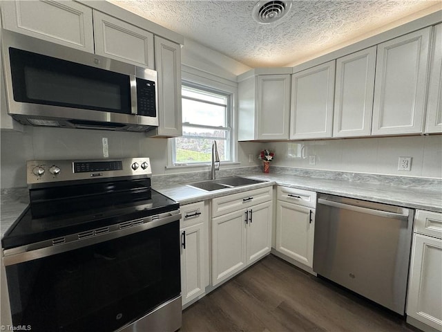 kitchen featuring dark wood-type flooring, white cabinets, sink, a textured ceiling, and stainless steel appliances