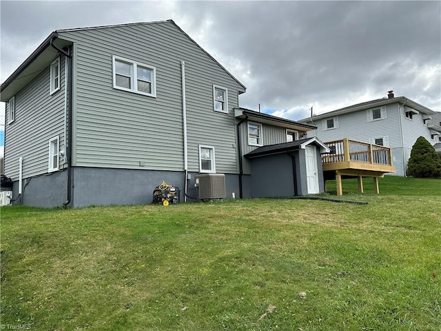 back of property with a lawn, central air condition unit, and a wooden deck