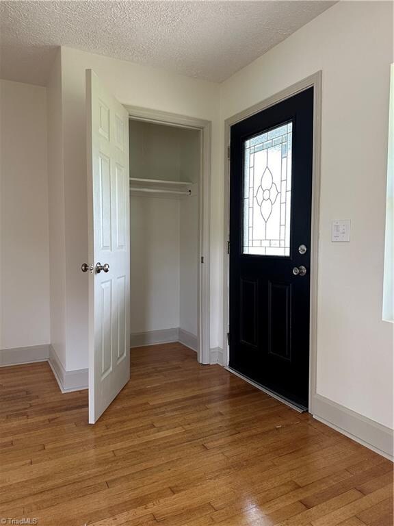 entrance foyer with light hardwood / wood-style floors and a textured ceiling