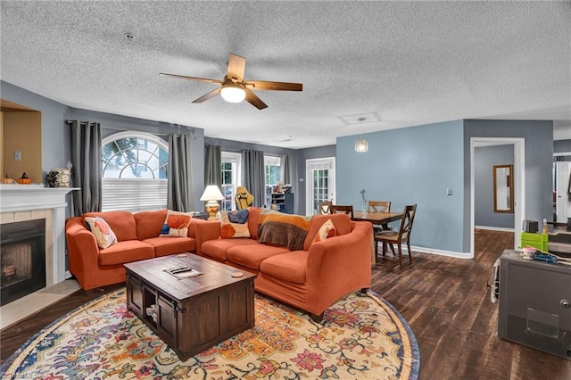 living room featuring a fireplace, wood-type flooring, a textured ceiling, and ceiling fan