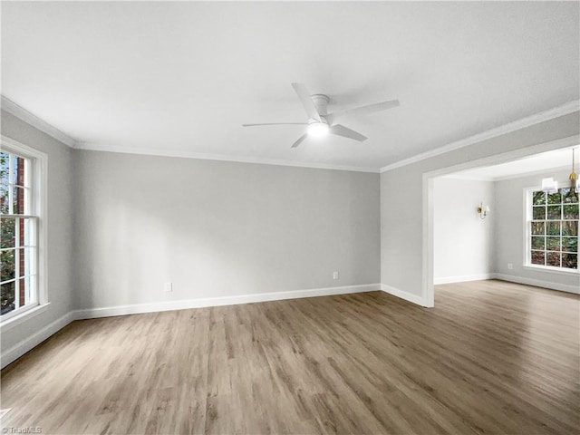 unfurnished room featuring hardwood / wood-style floors, ceiling fan with notable chandelier, ornamental molding, and a healthy amount of sunlight