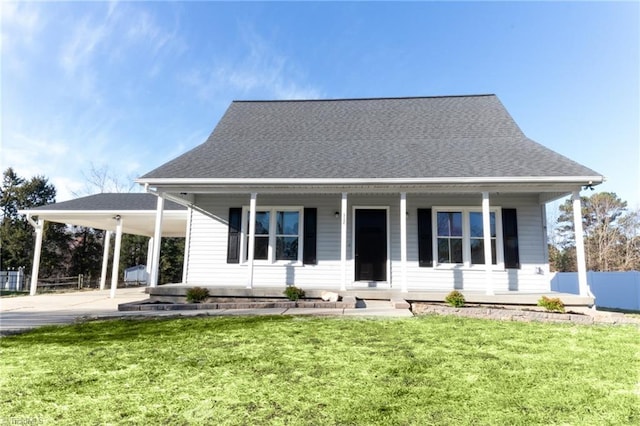 view of front of house with an attached carport, concrete driveway, roof with shingles, a front yard, and covered porch