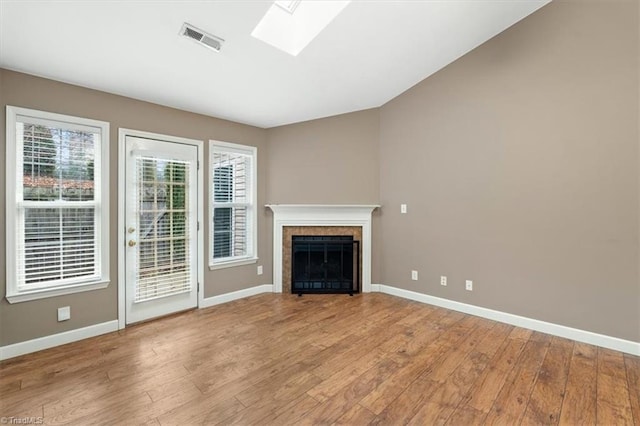 unfurnished living room featuring visible vents, a skylight, wood finished floors, and baseboards