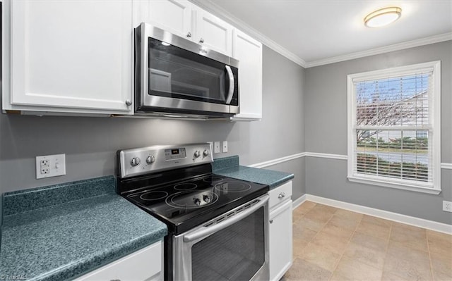 kitchen with dark countertops, white cabinets, ornamental molding, and stainless steel appliances