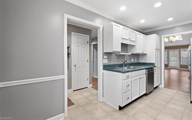 kitchen featuring dark countertops, a sink, white cabinets, dishwasher, and crown molding