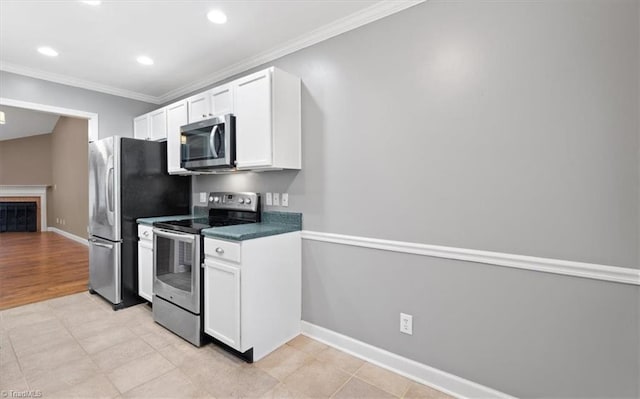 kitchen with white cabinets, stainless steel appliances, baseboards, and ornamental molding