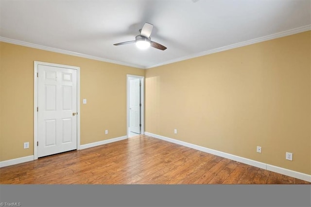 empty room with crown molding, baseboards, and wood finished floors