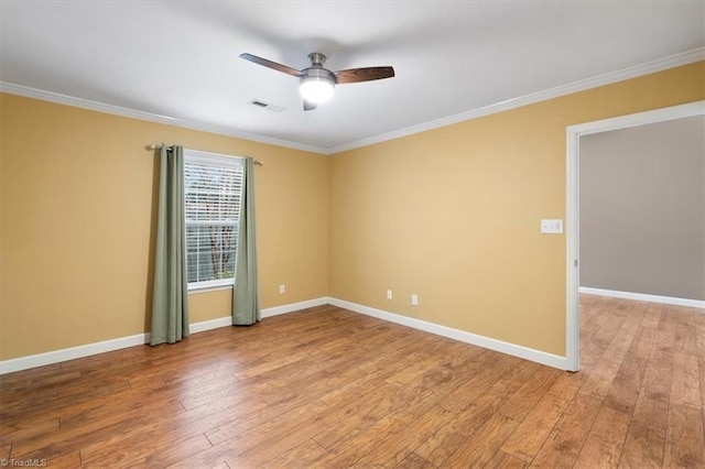 empty room with visible vents, a ceiling fan, crown molding, light wood finished floors, and baseboards