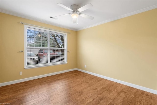 spare room with visible vents, light wood-type flooring, baseboards, and ornamental molding