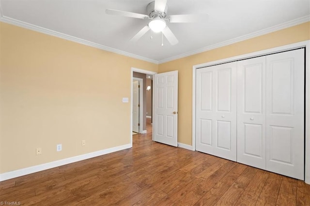 unfurnished bedroom featuring ceiling fan, a closet, ornamental molding, and hardwood / wood-style flooring