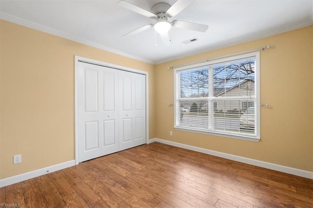 unfurnished bedroom featuring hardwood / wood-style flooring, ceiling fan, ornamental molding, and a closet