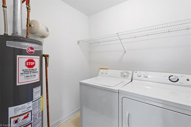 washroom featuring gas water heater, baseboards, laundry area, and washer and clothes dryer