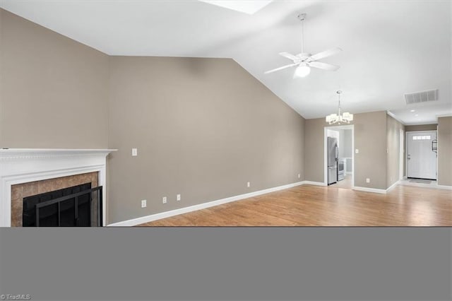 unfurnished living room with visible vents, ceiling fan with notable chandelier, a high end fireplace, light wood finished floors, and baseboards