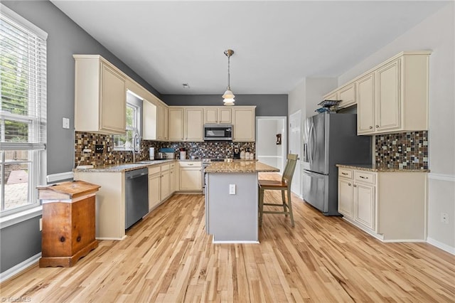 6416 Rock Springs Rd, Greensboro, NC 27410 - kitchen with stainless steel appliances, light wood-style floors, cream cabinetry, backsplash, and a breakfast bar