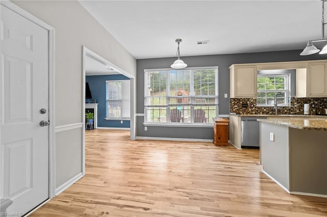 6416 Rock Springs Rd, Greensboro, NC 27410 - kitchen with stainless steel dishwasher, light wood-type flooring, backsplash, and light stone countertops
