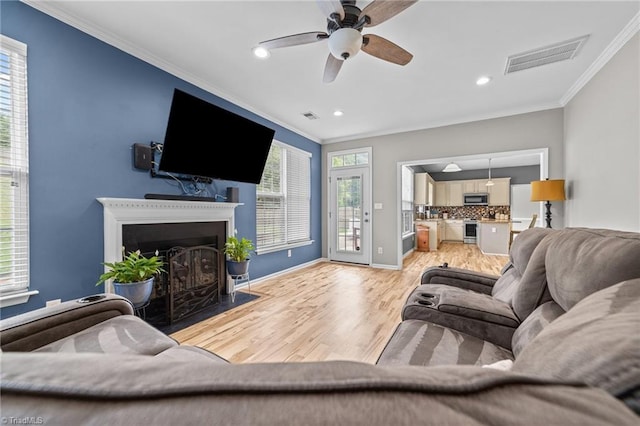 6416 Rock Springs Rd, Greensboro, NC 27410 - living room with crown molding, light wood-style floors, plenty of natural light, a ceiling fan, and a fireplace with flush hearth