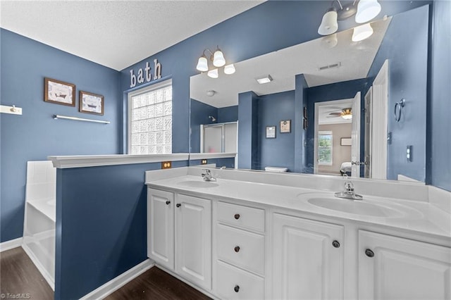 6416 Rock Springs Rd, Greensboro, NC 27410 - full bathroom featuring wood finished floors, a bath, double vanity, a textured ceiling, and ceiling fan