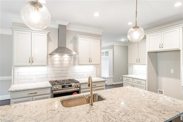 kitchen featuring light stone counters, ornamental molding, a sink, wall chimney range hood, and gas range