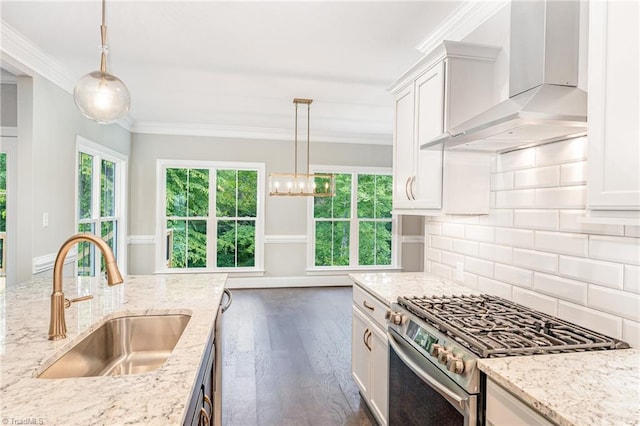 kitchen featuring a sink, white cabinetry, ornamental molding, stainless steel range with gas cooktop, and wall chimney exhaust hood