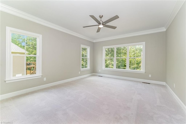 empty room with ceiling fan, light colored carpet, visible vents, baseboards, and ornamental molding